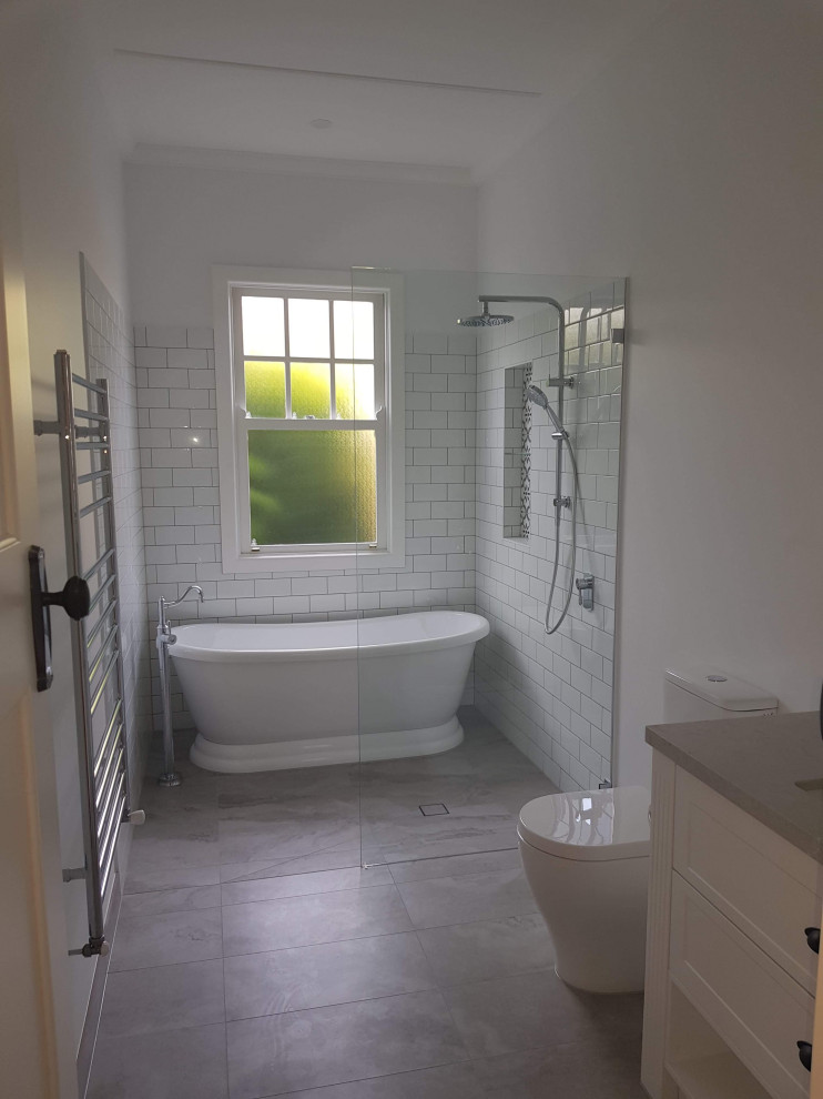 Стильный дизайн: маленькая главная ванная комната в викторианском стиле с фасадами в стиле шейкер, белыми фасадами, отдельно стоящей ванной, открытым душем, раздельным унитазом, белой плиткой, керамической плиткой, белыми стенами, полом из керамогранита, врезной раковиной, столешницей из искусственного кварца, разноцветным полом, открытым душем, серой столешницей, нишей, тумбой под одну раковину, встроенной тумбой и деревянным потолком для на участке и в саду - последний тренд