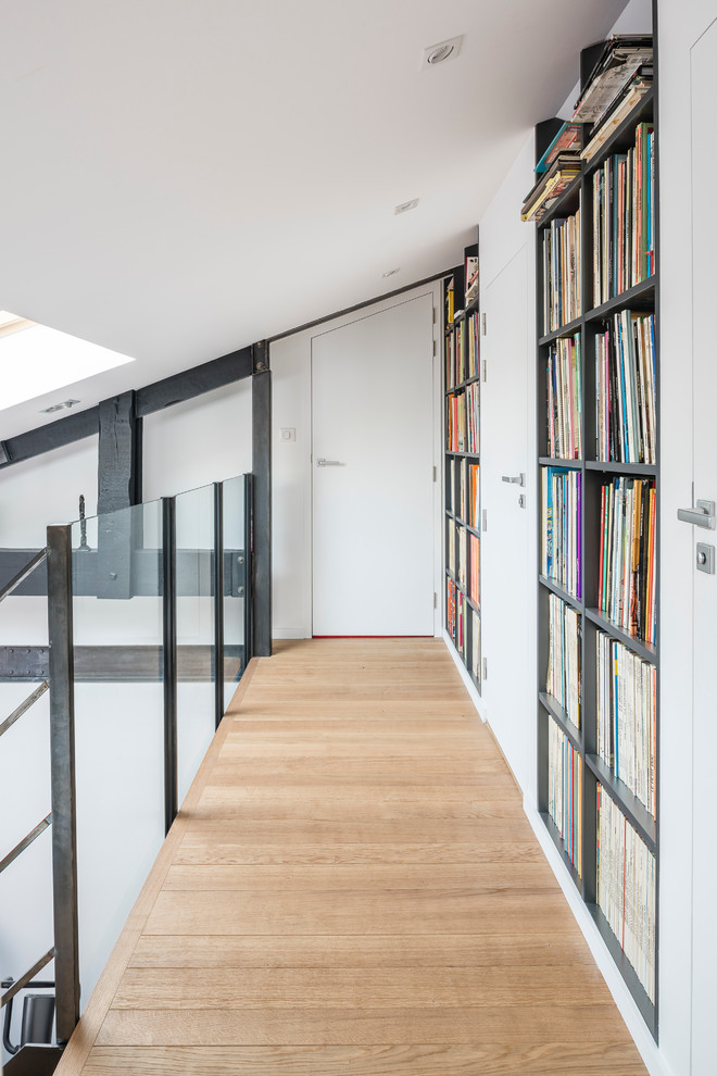 This is an example of a mid-sized contemporary hallway in Nantes with white walls and light hardwood floors.