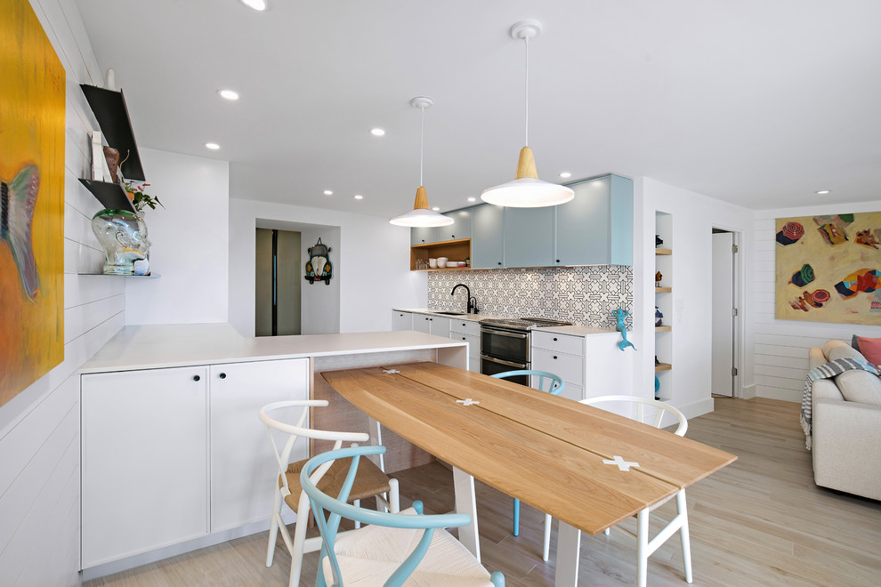 Inspiration for a small beach style eat-in kitchen in Tampa with an undermount sink, shaker cabinets, white cabinets, quartzite benchtops, ceramic splashback, stainless steel appliances, ceramic floors, a peninsula and beige floor.