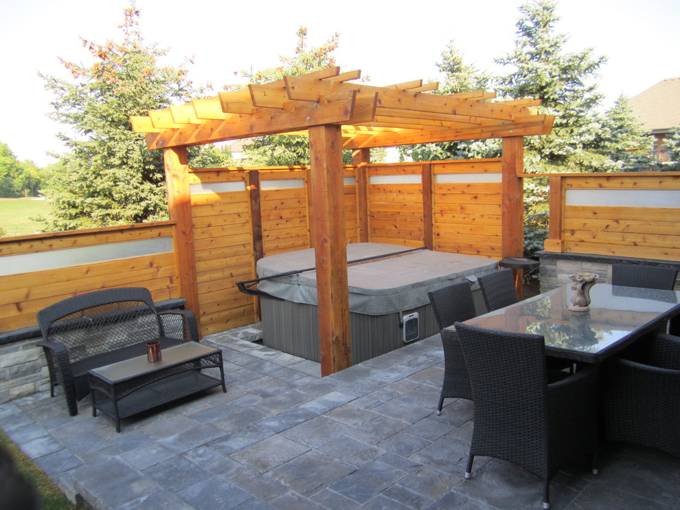 Inspiration for a large contemporary backyard patio in Toronto with natural stone pavers and a pergola.