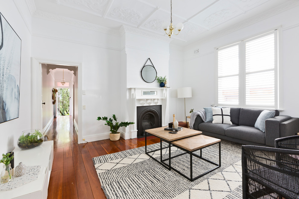 Inspiration for a transitional formal living room in Sydney with white walls, medium hardwood floors, a standard fireplace, no tv and brown floor.
