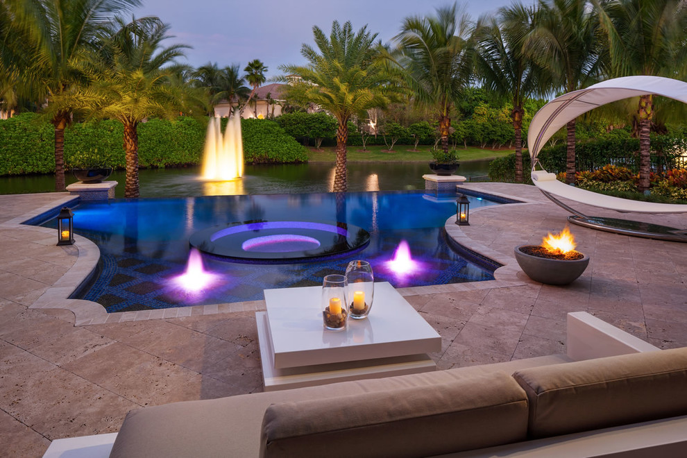 This is an example of a mid-sized tropical backyard custom-shaped infinity pool in Miami with a hot tub and tile.