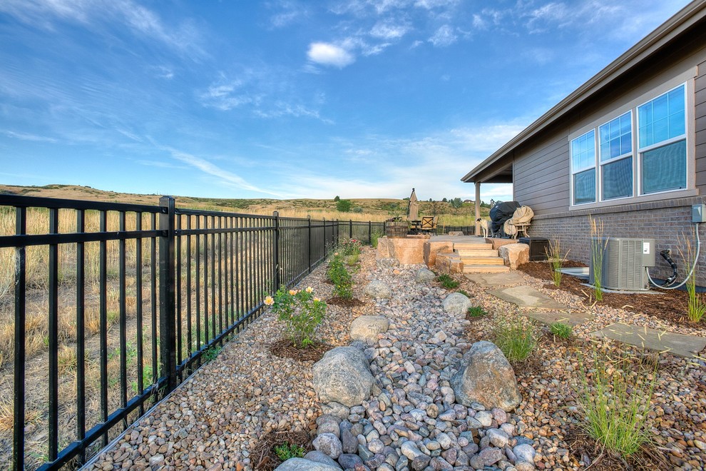 This is an example of a large and desert look backyard partial sun xeriscape in Denver with natural stone pavers.