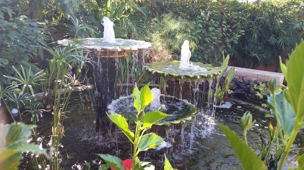 This is an example of a mid-sized transitional partial sun backyard stone water fountain landscape in Phoenix.