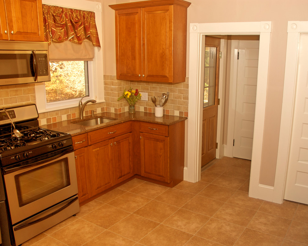 Photo of a mid-sized traditional l-shaped kitchen pantry in Boston with a single-bowl sink, raised-panel cabinets, medium wood cabinets, quartz benchtops, beige splashback, ceramic splashback, stainless steel appliances, linoleum floors and with island.