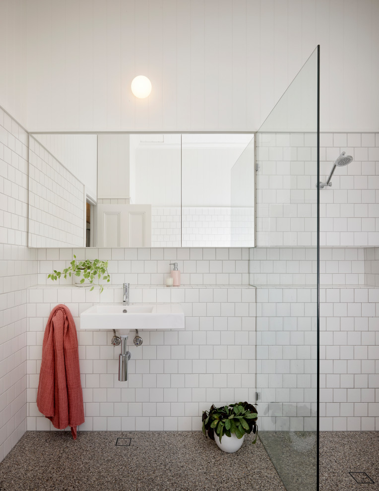 Photo of a mid-sized contemporary kids bathroom in Brisbane with an open shower, white tile, white walls, a wall-mount sink, tile benchtops, grey floor, a hinged shower door, white benchtops and a single vanity.