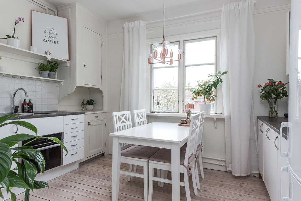 Mid-sized scandinavian eat-in kitchen in Stockholm with flat-panel cabinets, white cabinets and white splashback.
