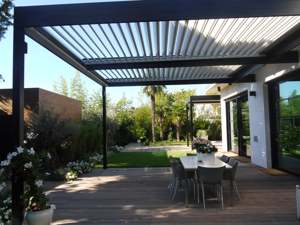 Photo of a large modern side yard patio in New York with decking and a pergola.