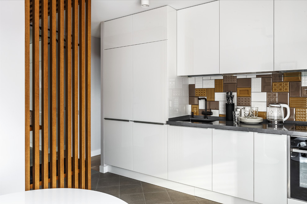 Inspiration for a contemporary single-wall separate kitchen in Moscow with an undermount sink, flat-panel cabinets, white cabinets, multi-coloured splashback, ceramic splashback, black appliances, no island, black benchtop and grey floor.