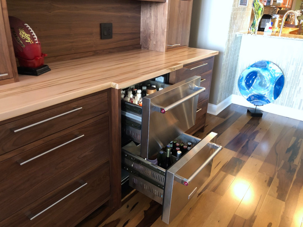 Photo of a mid-sized modern home bar in Tampa with no sink, flat-panel cabinets, medium wood cabinets, wood benchtops, timber splashback and multi-coloured benchtop.