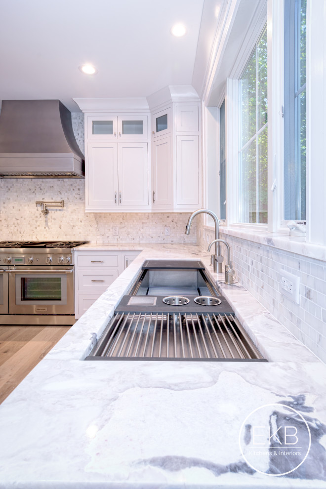 Example of a large l-shaped medium tone wood floor and brown floor open concept kitchen design in New York with an undermount sink, shaker cabinets, white cabinets, quartz countertops, multicolored backsplash, ceramic backsplash, paneled appliances, an island and multicolored countertops