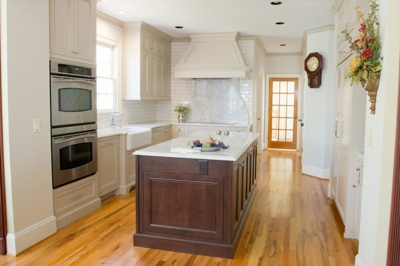 Inspiration for a transitional medium tone wood floor kitchen remodel in Atlanta with a farmhouse sink, beige cabinets, quartzite countertops and an island