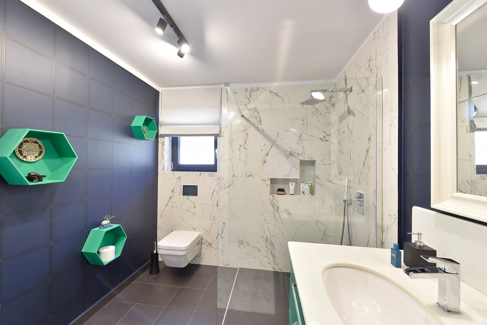 Contemporary kids bathroom in Other with white cabinets, an open shower, a wall-mount toilet, white tile, porcelain tile, blue walls, laminate floors, laminate benchtops, black floor and an open shower.