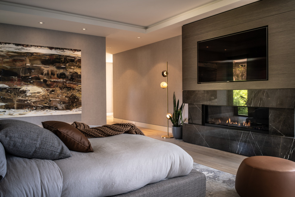 Bedroom - large contemporary master light wood floor, beige floor and wallpaper bedroom idea in Vancouver with gray walls, a standard fireplace and a stone fireplace