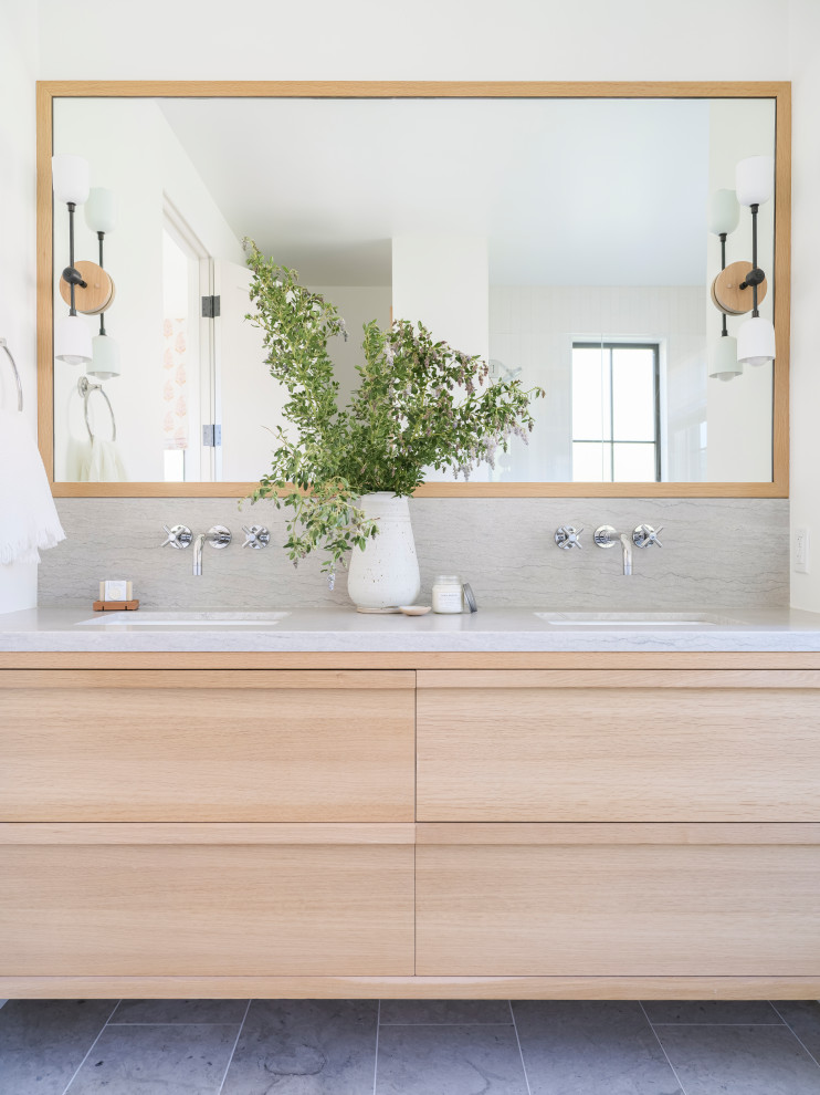 Example of a mid-sized beach style master gray tile and limestone tile limestone floor, gray floor and double-sink bathroom design in Los Angeles with shaker cabinets, light wood cabinets, a one-piece toilet, white walls, an undermount sink, a hinged shower door, gray countertops and a floating vanity