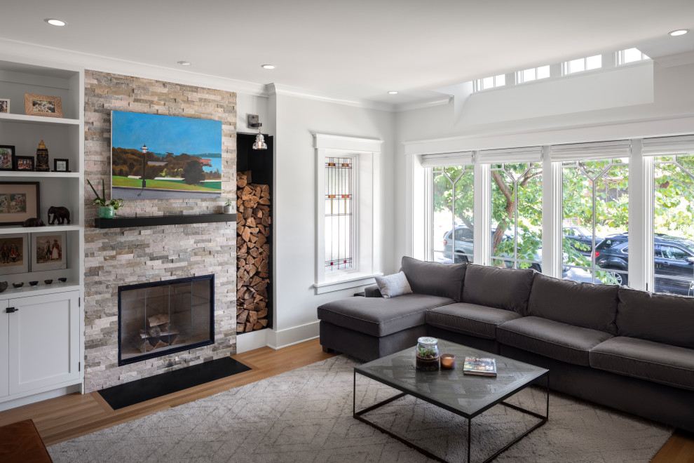 Photo of a mid-sized transitional enclosed living room in Chicago with grey walls, a standard fireplace, a wall-mounted tv and beige floor.