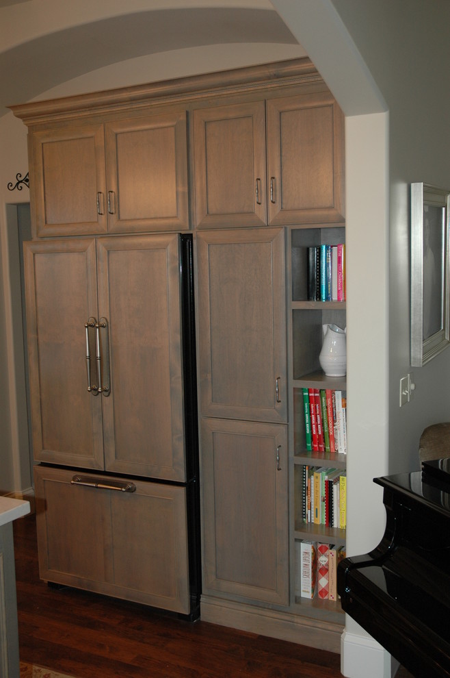 Example of a large transitional u-shaped medium tone wood floor kitchen pantry design with a farmhouse sink, flat-panel cabinets, white cabinets, granite countertops, brown backsplash, stone tile backsplash, paneled appliances and an island