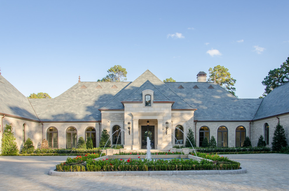 Design ideas for an expansive mediterranean beige exterior in Houston with stone veneer and a gable roof.