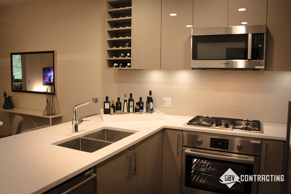 Example of a small minimalist u-shaped eat-in kitchen design in Calgary with beige backsplash, stainless steel appliances and an island