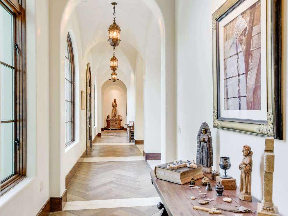 Photo of a mediterranean hallway in Austin with white walls and brown floor.