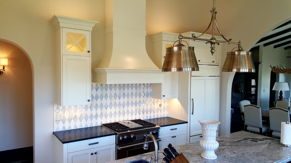 Inspiration for a large traditional l-shaped kitchen pantry in San Francisco with a farmhouse sink, recessed-panel cabinets, white cabinets, soapstone benchtops, blue splashback, ceramic splashback, stainless steel appliances, dark hardwood floors and with island.
