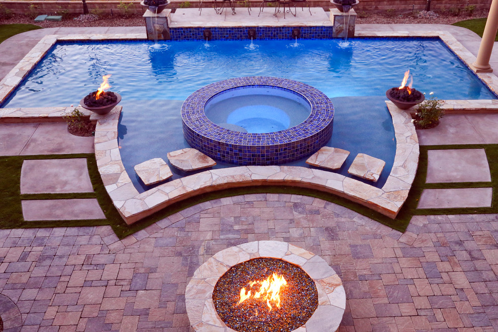 Photo of a mid-sized transitional backyard custom-shaped natural pool in Orange County with a hot tub and natural stone pavers.
