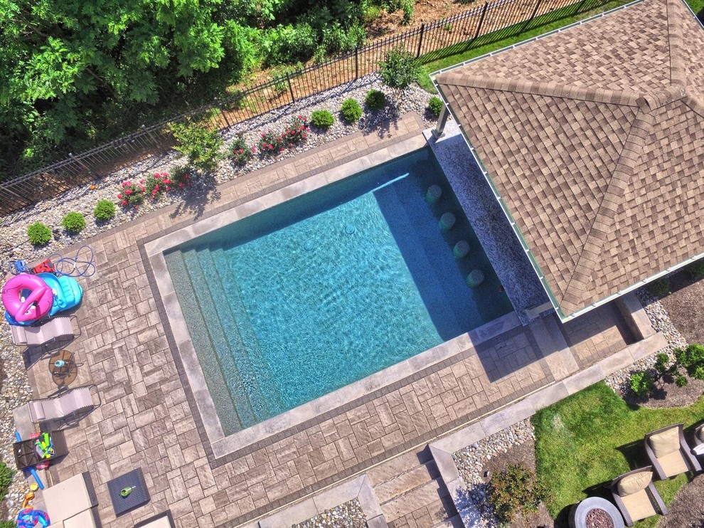 This is an example of a large transitional backyard rectangular lap pool in Philadelphia with a pool house and concrete pavers.