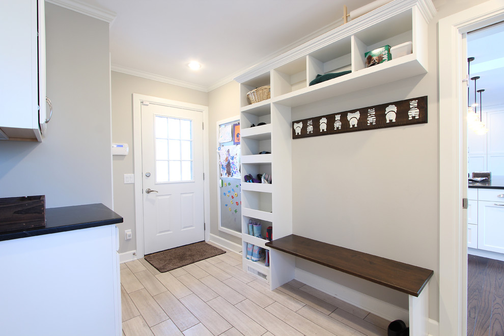 Mid-sized transitional u-shaped utility room in Other with a single-bowl sink, flat-panel cabinets, white cabinets, soapstone benchtops, grey walls, limestone floors and a stacked washer and dryer.