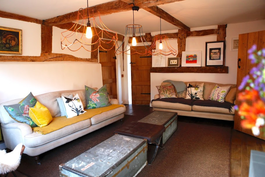 Inspiration for a country living room in Other with dark hardwood floors, a brick fireplace surround and exposed beam.