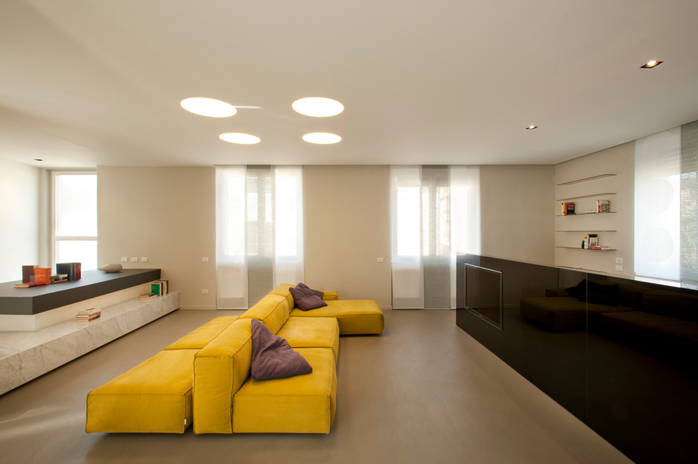 This is an example of a contemporary open concept living room in Milan with white walls and a wall-mounted tv.