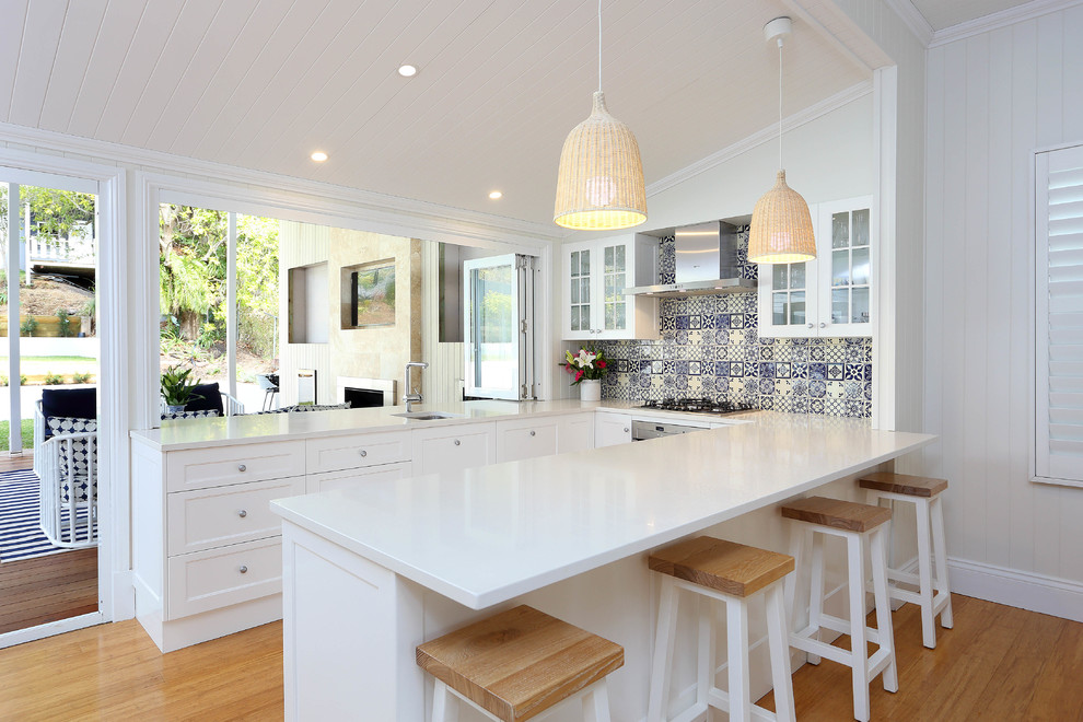 Photo of a mid-sized traditional galley kitchen in Brisbane with a drop-in sink, shaker cabinets, white cabinets, laminate benchtops, blue splashback, stone tile splashback, stainless steel appliances, bamboo floors and no island.