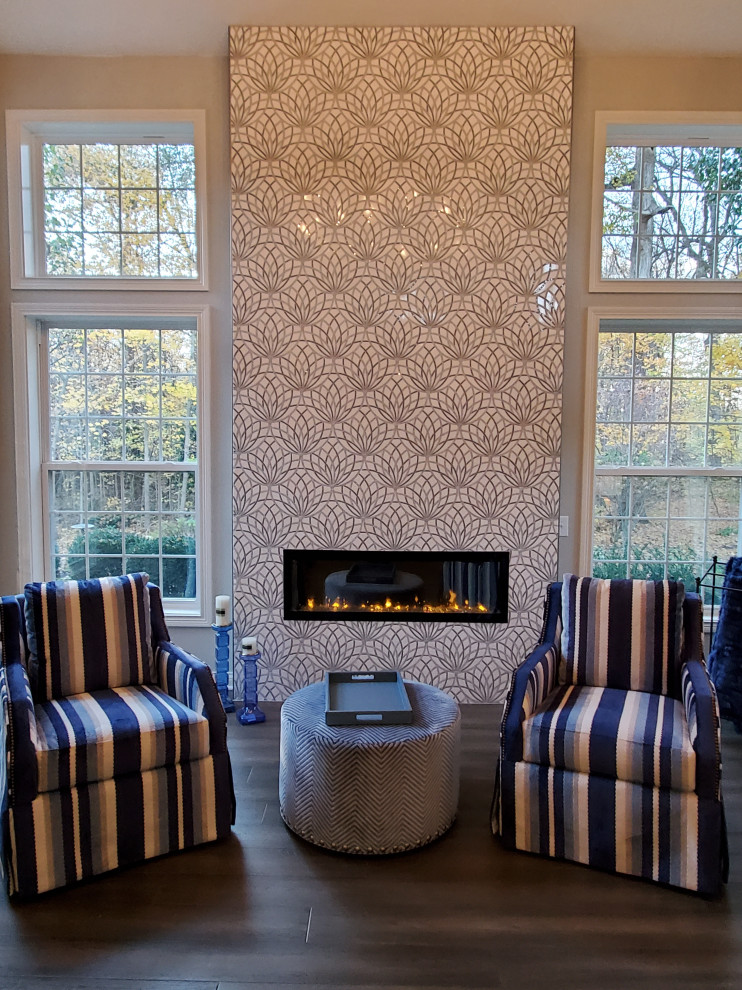 This is an example of a mid-sized transitional open concept family room in Indianapolis with grey walls, medium hardwood floors, a standard fireplace, a tile fireplace surround and grey floor.