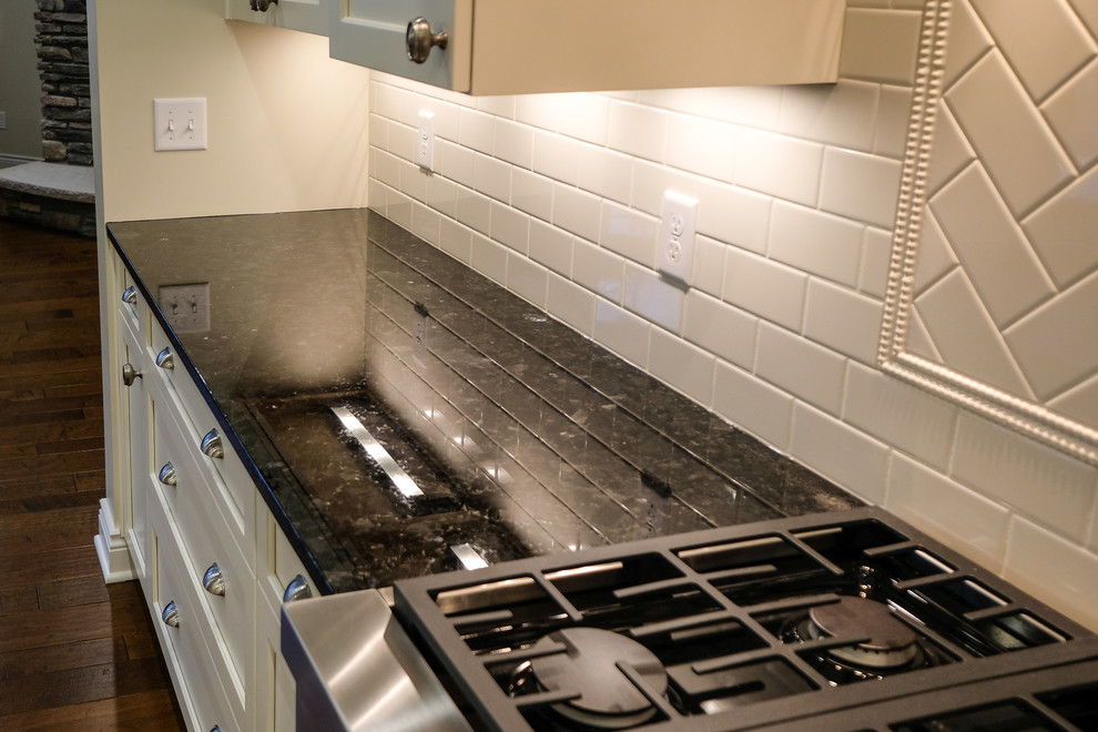 Inspiration for a large transitional l-shaped dark wood floor and brown floor eat-in kitchen remodel with an undermount sink, recessed-panel cabinets, white cabinets, granite countertops, white backsplash, stainless steel appliances, an island and blue countertops