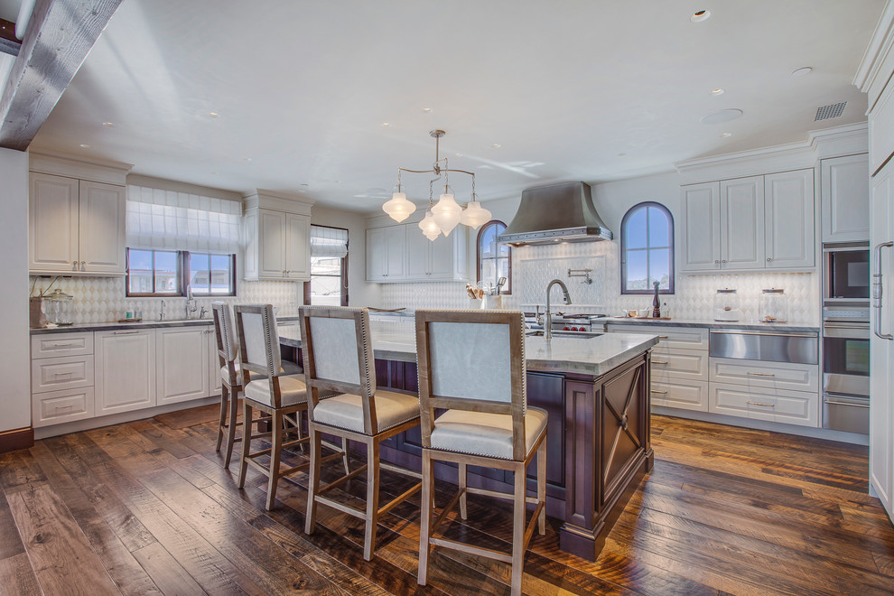 Open concept kitchen - large mediterranean u-shaped medium tone wood floor open concept kitchen idea in Los Angeles with an undermount sink, raised-panel cabinets, white cabinets, granite countertops, white backsplash, ceramic backsplash, stainless steel appliances and an island