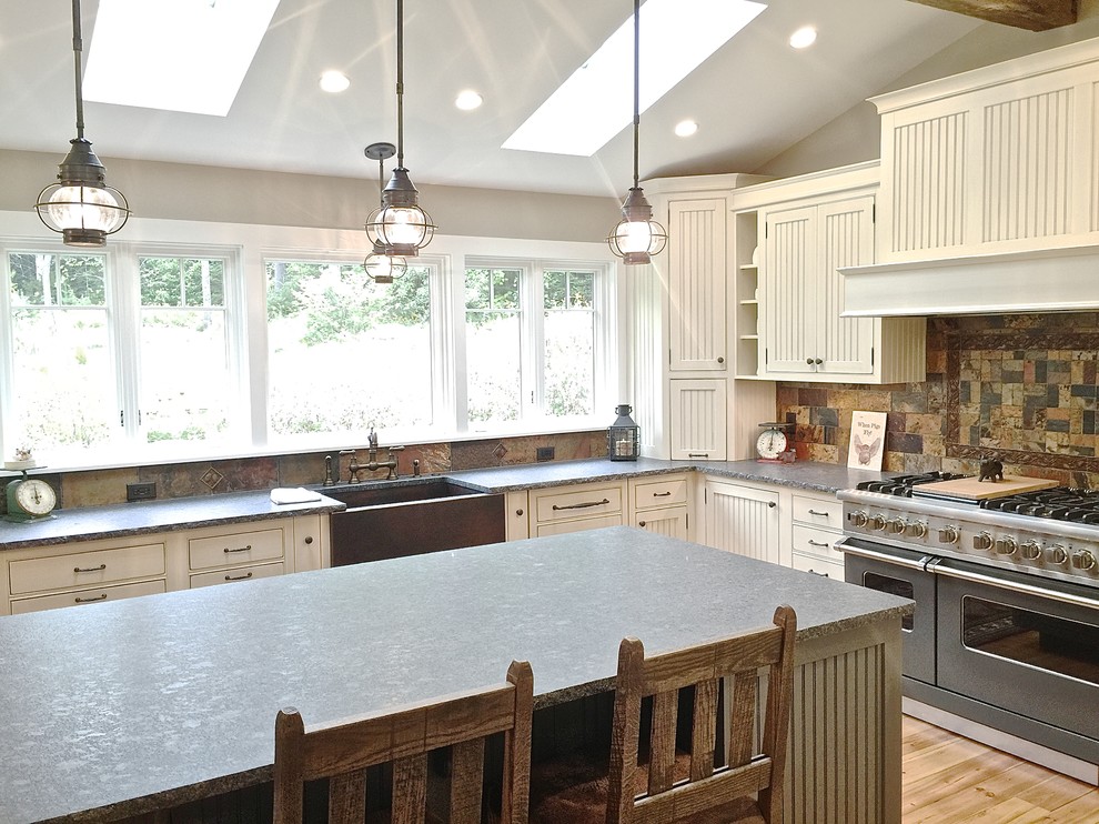 Example of a large transitional u-shaped light wood floor eat-in kitchen design in Burlington with a farmhouse sink, beaded inset cabinets, distressed cabinets, granite countertops, multicolored backsplash, stone tile backsplash, paneled appliances and an island