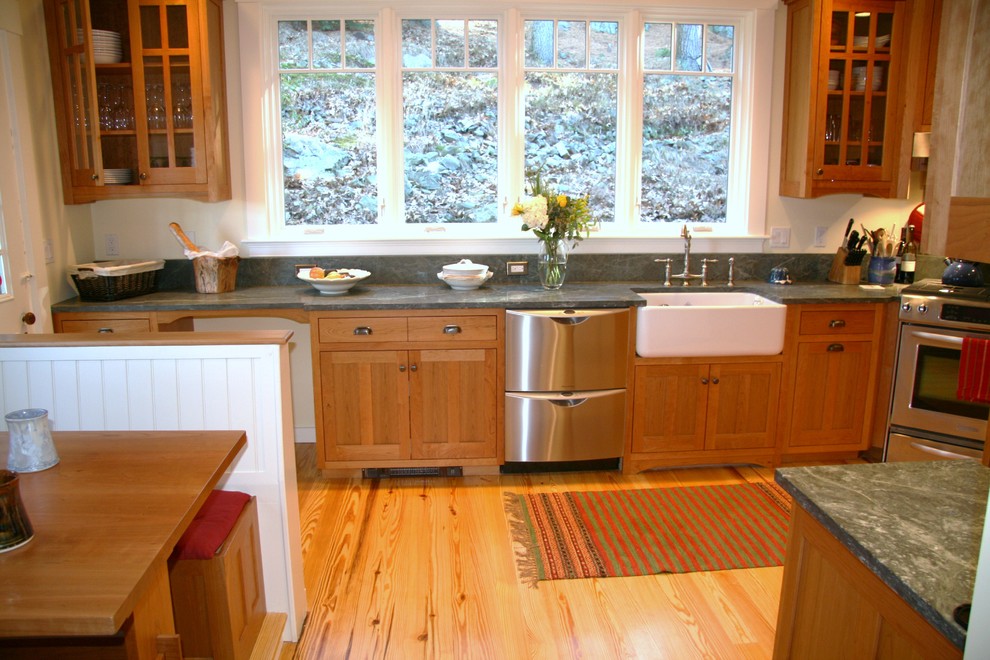 This is an example of a large arts and crafts l-shaped eat-in kitchen in Boston with a farmhouse sink, beaded inset cabinets, medium wood cabinets, granite benchtops, stainless steel appliances, light hardwood floors and with island.