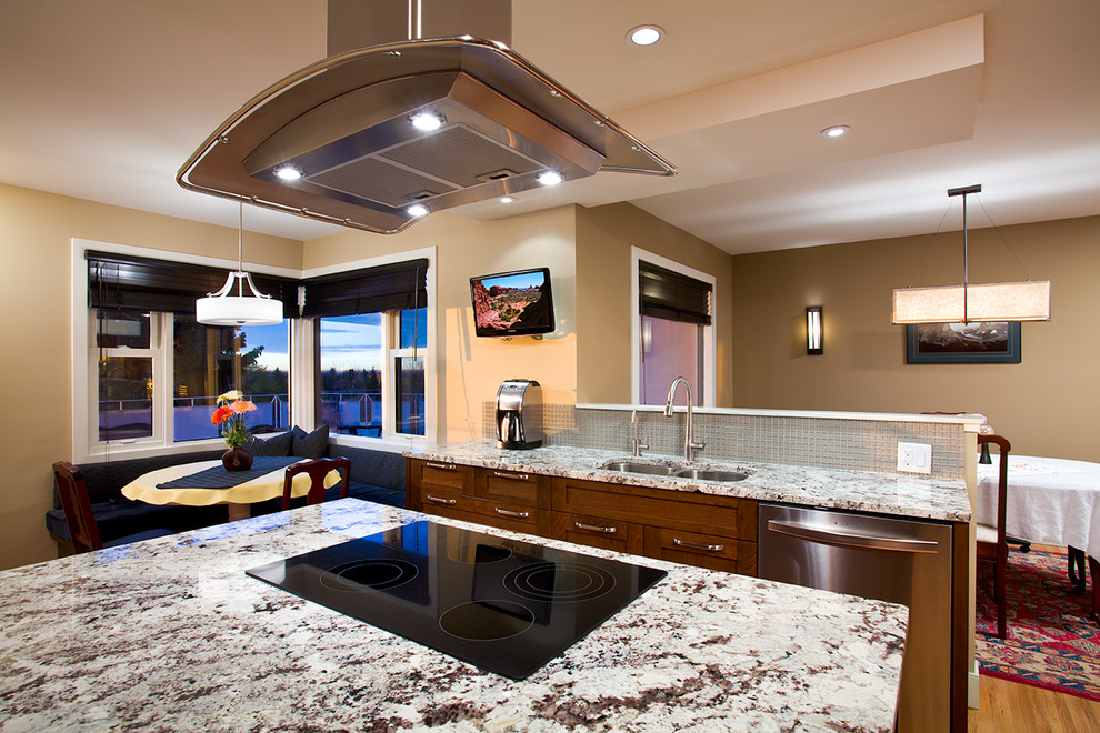 Inspiration for a transitional u-shaped light wood floor enclosed kitchen remodel in Calgary with an undermount sink, shaker cabinets, medium tone wood cabinets, granite countertops, beige backsplash, glass tile backsplash, stainless steel appliances and an island