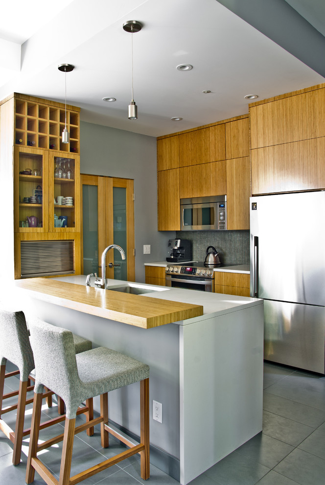 Photo of a modern galley kitchen in Vancouver with stainless steel appliances, wood benchtops, a single-bowl sink, flat-panel cabinets and medium wood cabinets.