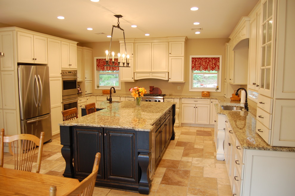 This is an example of a large traditional u-shaped eat-in kitchen in Philadelphia with an undermount sink, recessed-panel cabinets, white cabinets, granite benchtops, stainless steel appliances, travertine floors, with island and beige floor.