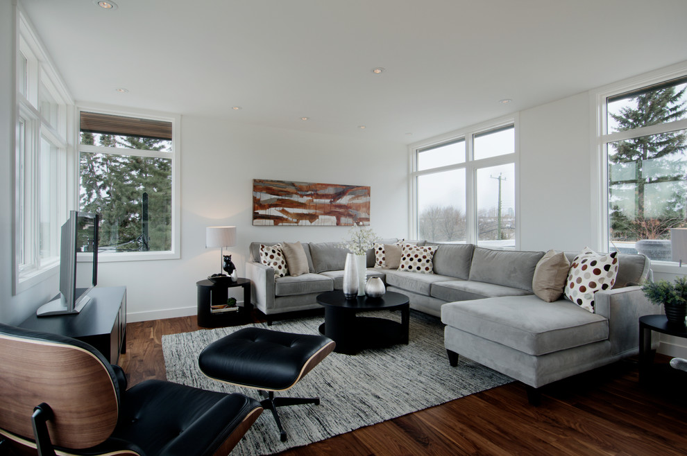 Contemporary family room in Calgary with white walls, dark hardwood floors and a freestanding tv.