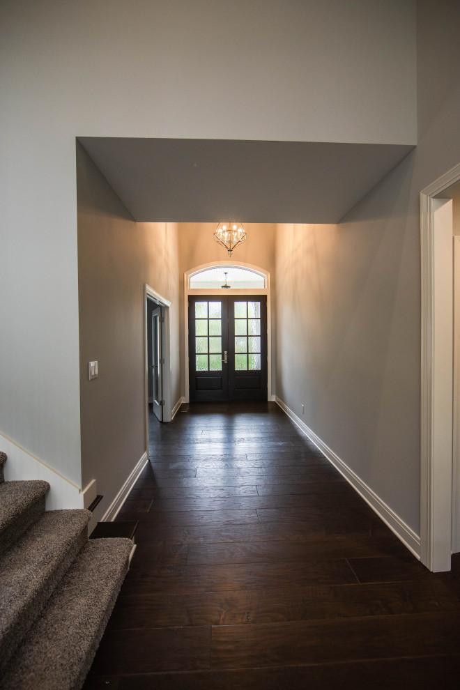 Großer Klassischer Eingang mit Korridor, grauer Wandfarbe, dunklem Holzboden, Doppeltür, dunkler Holzhaustür, braunem Boden und gewölbter Decke in Indianapolis