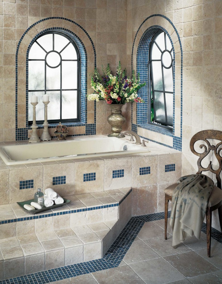 Photo of a large mediterranean master bathroom in Charlotte with a drop-in tub, beige tile, brown tile, stone tile, beige walls, limestone floors and beige floor.