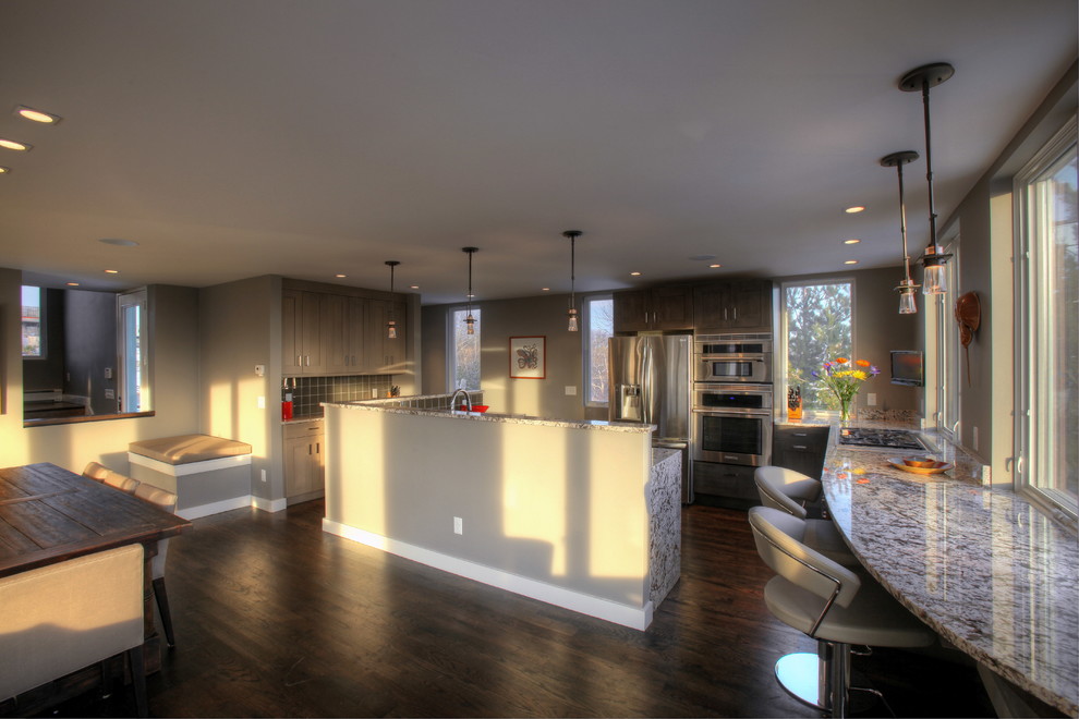 Eat-in kitchen - large transitional u-shaped dark wood floor and brown floor eat-in kitchen idea in Boston with a double-bowl sink, shaker cabinets, gray cabinets, granite countertops, gray backsplash, glass tile backsplash, stainless steel appliances and an island