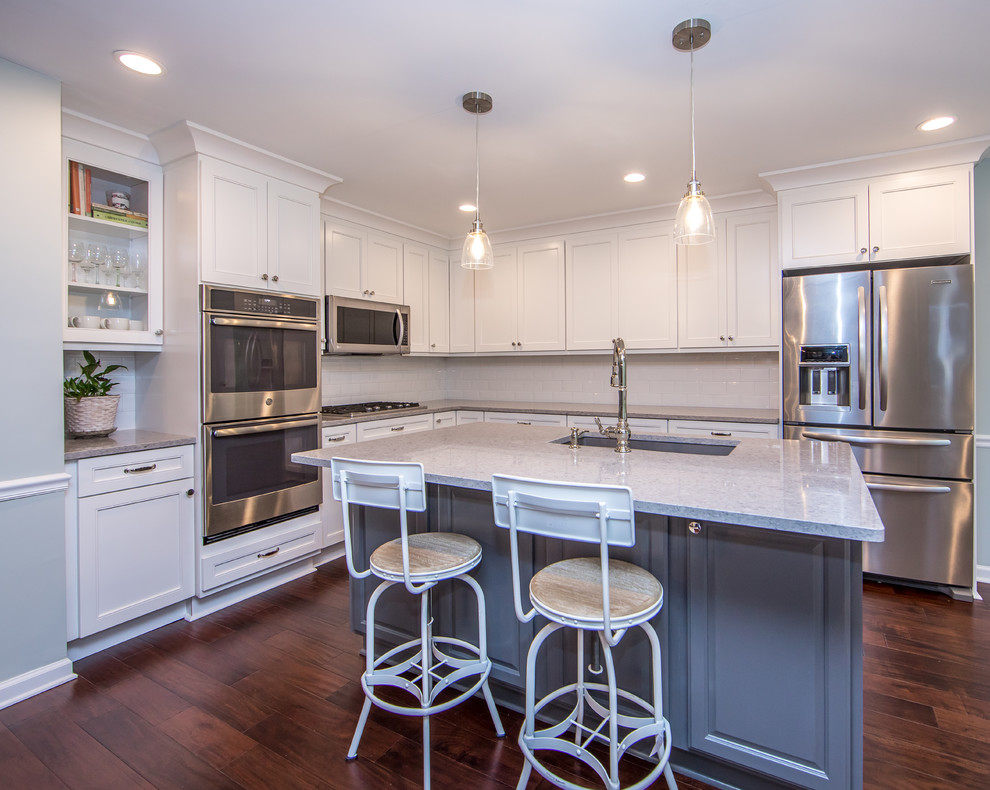 Example of a mid-sized transitional l-shaped brown floor eat-in kitchen design in Atlanta with an undermount sink, white cabinets, quartzite countertops, white backsplash, subway tile backsplash, stainless steel appliances, an island and gray countertops