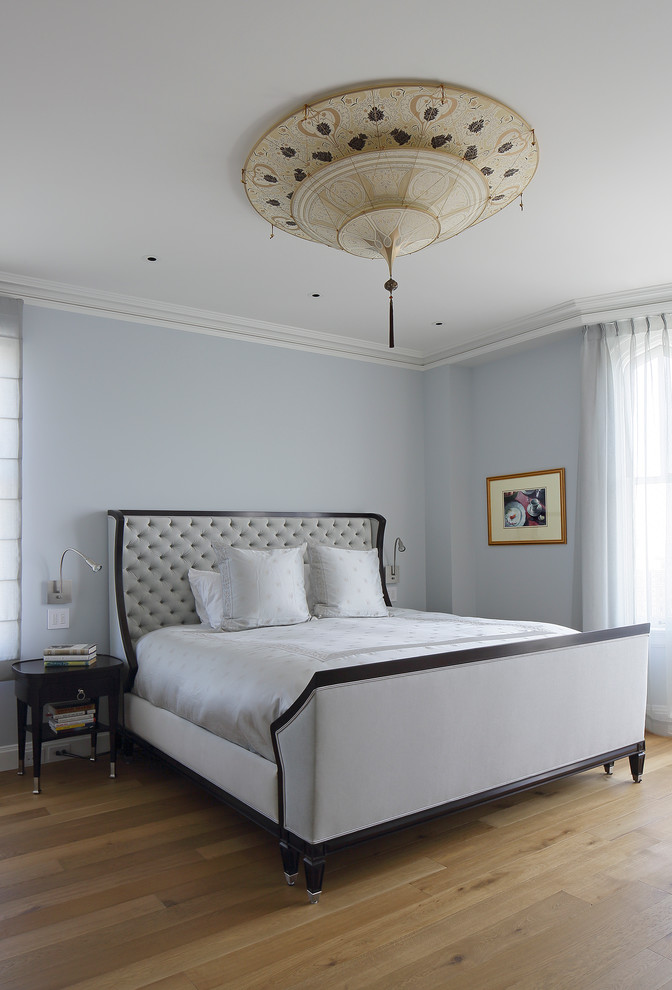 Traditional master bedroom in New York with blue walls and light hardwood floors.
