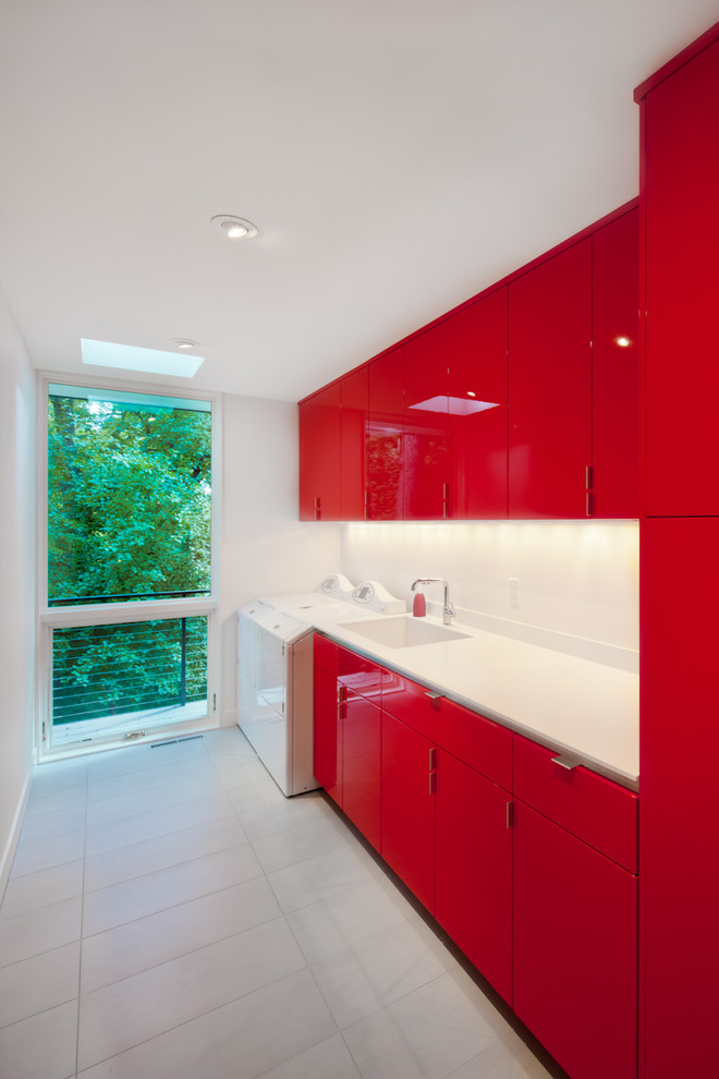 Photo of a large contemporary single-wall dedicated laundry room in Orange County with an undermount sink, flat-panel cabinets, red cabinets, quartzite benchtops, white walls, slate floors, a side-by-side washer and dryer and grey floor.
