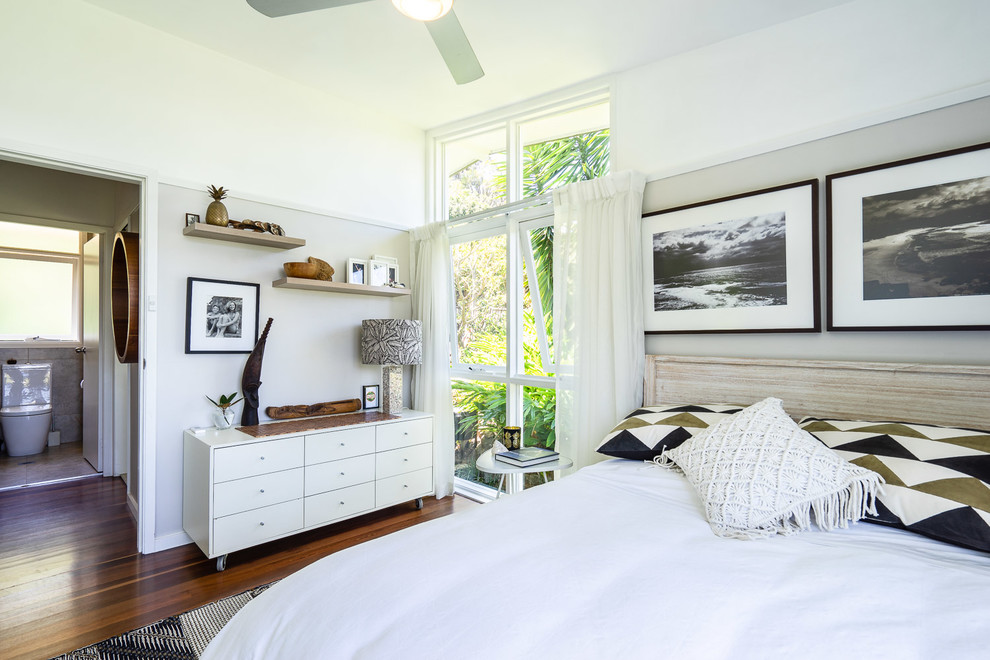 Beach style master bedroom in Sydney with beige walls, dark hardwood floors and brown floor.