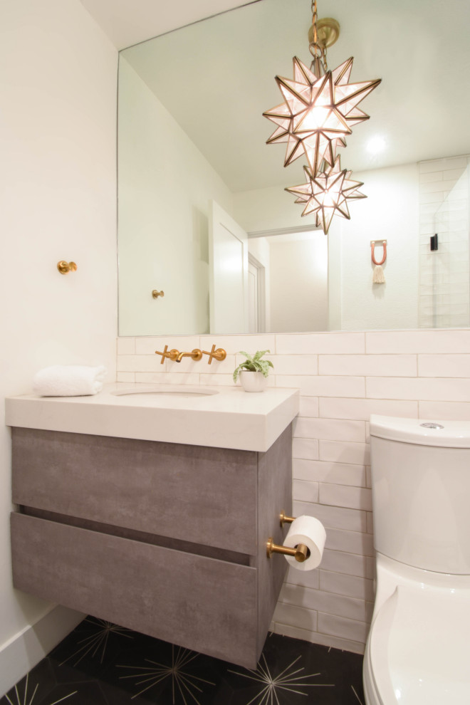 This is an example of a small country powder room in Other with flat-panel cabinets, grey cabinets, a two-piece toilet, black and white tile, ceramic tile, white walls, cement tiles, an integrated sink, engineered quartz benchtops, black floor, white benchtops and a floating vanity.