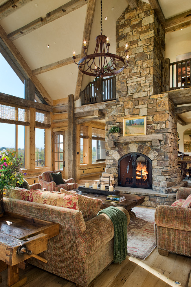 Inspiration for a country living room in Other with beige walls, light hardwood floors, a two-sided fireplace, a stone fireplace surround and no tv.