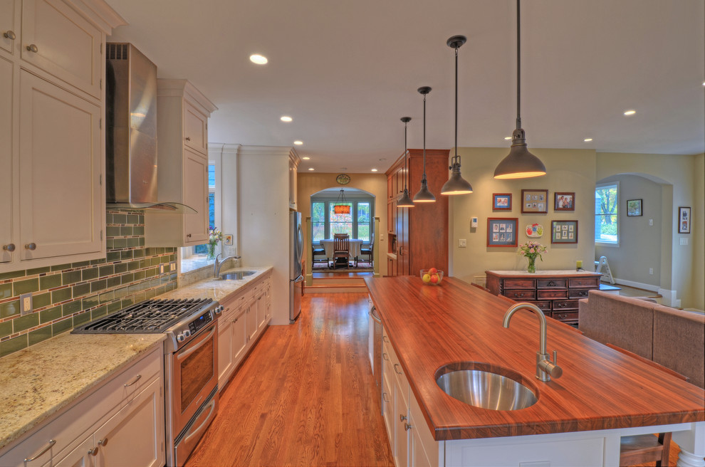 Inspiration for a large transitional medium tone wood floor open concept kitchen remodel in DC Metro with an undermount sink, shaker cabinets, white cabinets, granite countertops, green backsplash, subway tile backsplash, stainless steel appliances and an island
